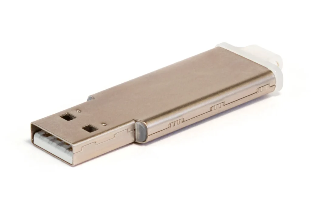Beyaz zemin üzerinde metal gövdeli, bağlantı ucu açık USB bellek.